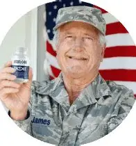 Veteran holding VisiFlora vision support supplement with American flag background. Professional product endorsement for eye health.